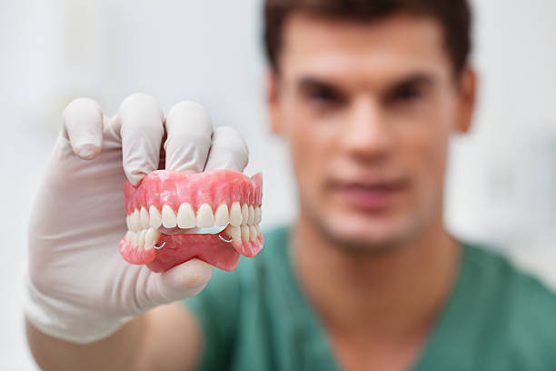 Dentista con dentadura postiza en la mano